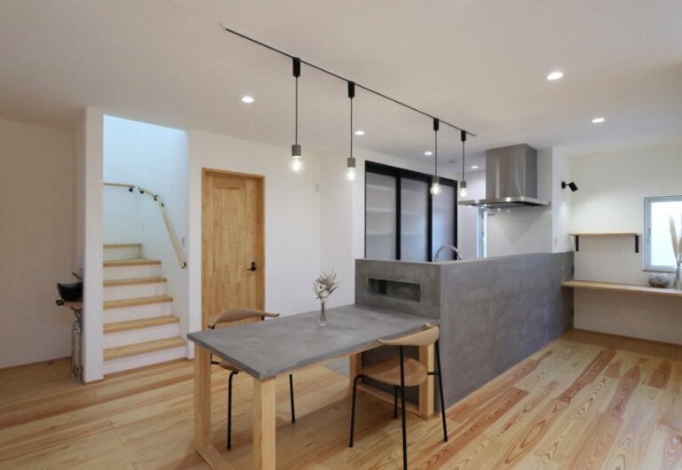 モルタル調のダイニングテーブルとキッチン